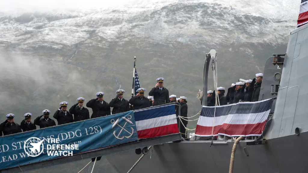 Sailors assigned to the destroyer USS Ted Stevens salute