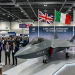 Concept model of the Global Combat Air Programme fighter displayed during an official event with UK, Italian, and Japanese flags.